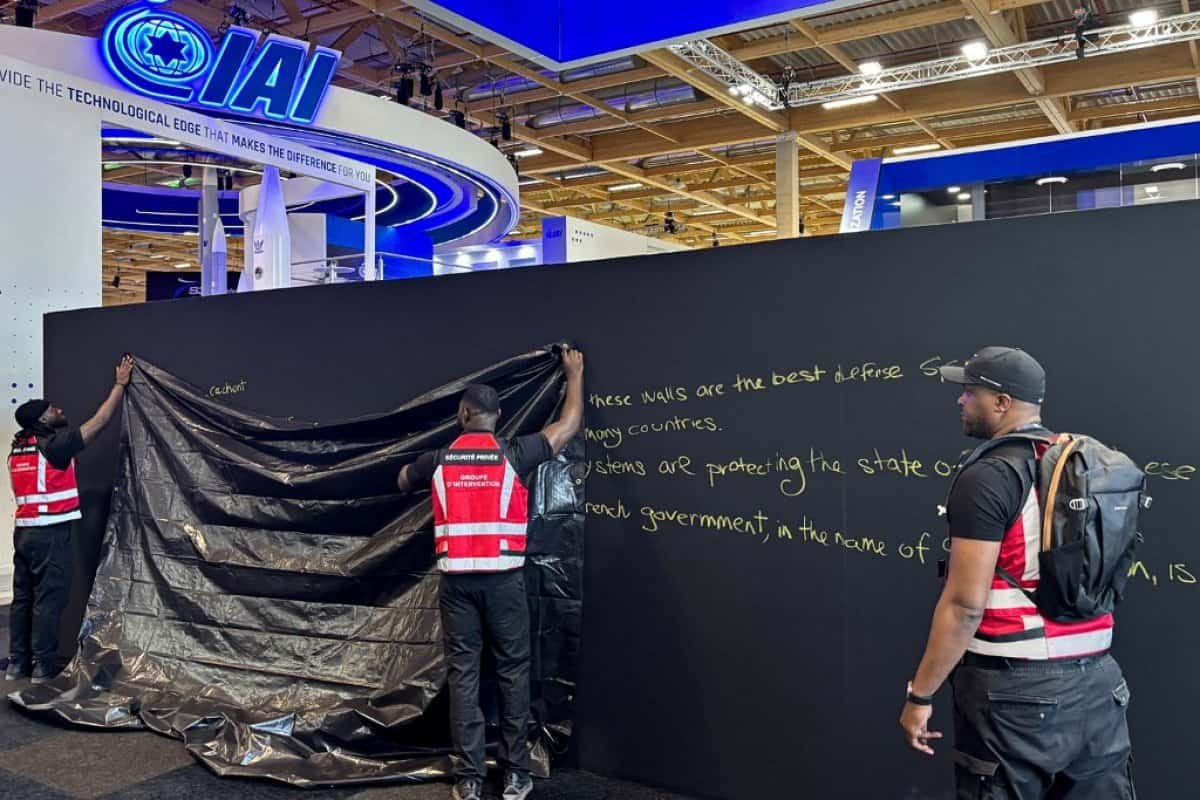 Des agents de sécurité hissent une bâche noire devant le pavillon israélien IAI au Salon du Bourget 2025, sur ordre du gouvernement français