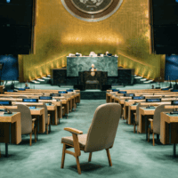 Hémicycle de l’Assemblée générale des Nations unies, un siège de délégation vide au premier plan, sur fond du vote commenté par la mission France ONU Genève