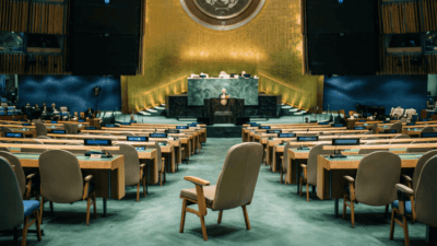 Hémicycle de l’Assemblée générale des Nations unies, un siège de délégation vide au premier plan, sur fond du vote commenté par la mission France ONU Genève