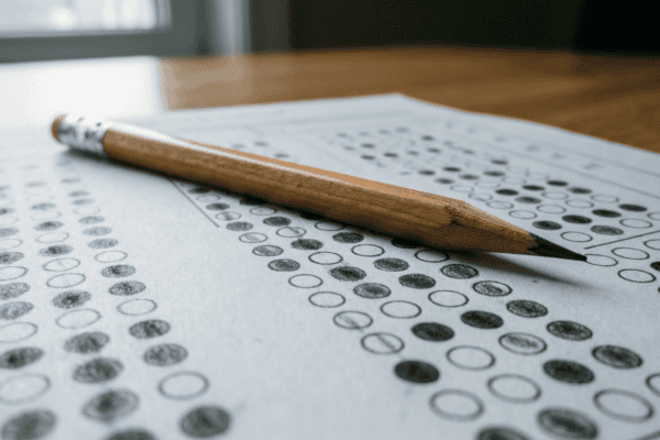 Grille de réponses à choix multiples et crayon, illustrant l’examen civique obligatoire pour les étrangers